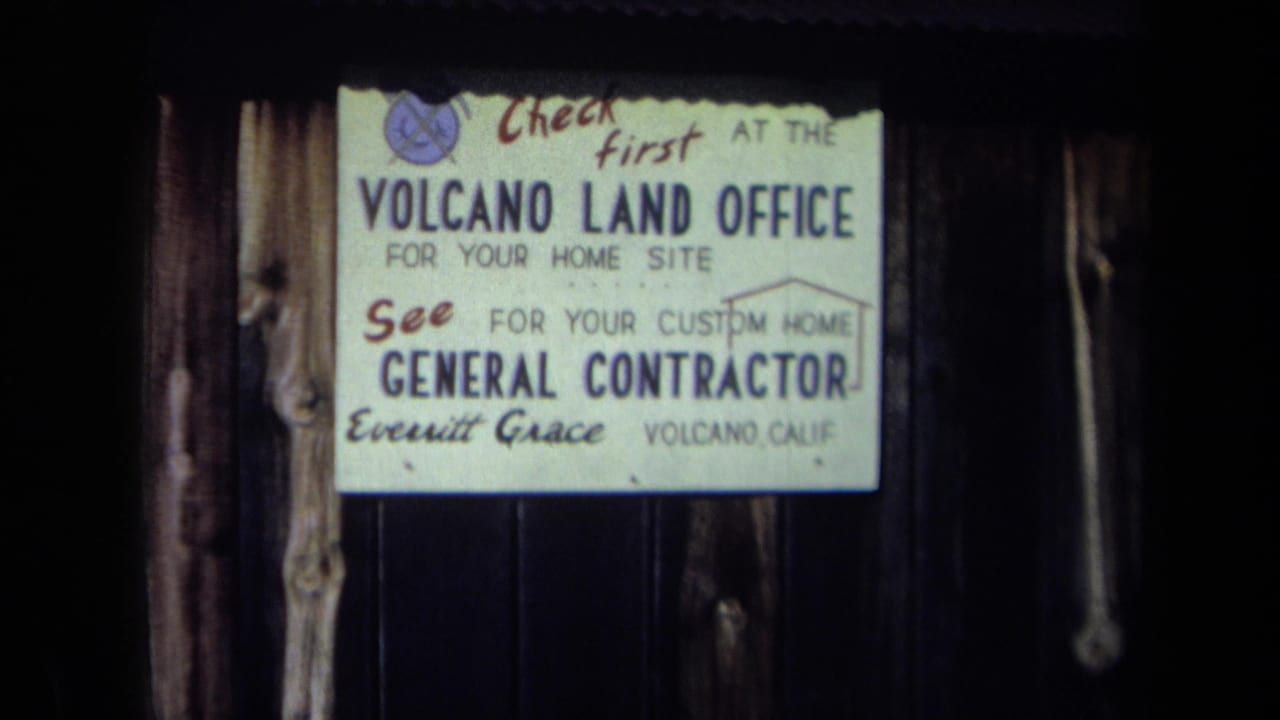 1969 California 8mm frame showing a Volcano Land Office sign advertising home sites and a general contractor.