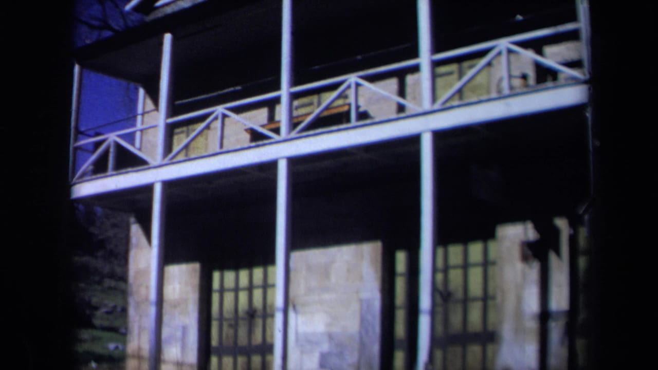 1969 California 8mm frame showing a historic hall exterior with stone facade, upper balcony, white posts, and dark film borders.