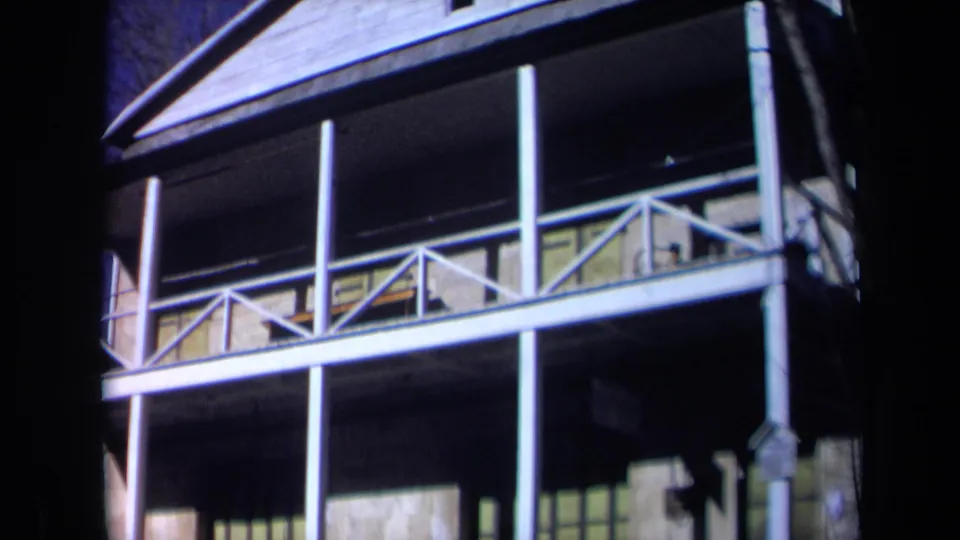 Final 1969 California frame of the historic hall exterior, with balcony posts, railings, stone facade, and visible 8mm film borders.