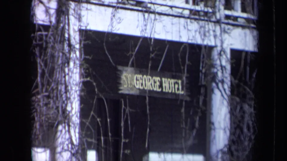 St. George Hotel sign visible through bare vines on a California hotel exterior in the 1969 home-movie footage.