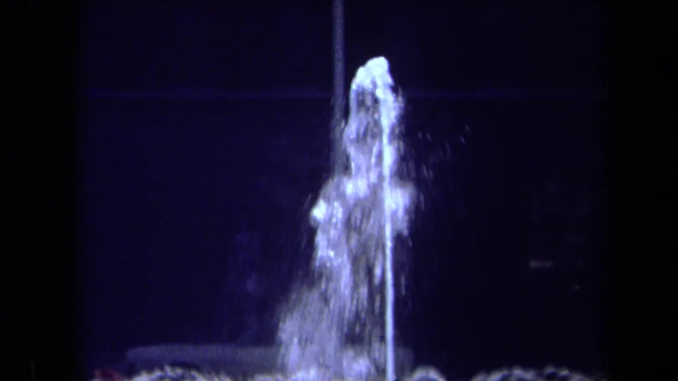 1969 California 8mm frame with the camera closer on the fountain spout, showing bright water spray against a dark background.