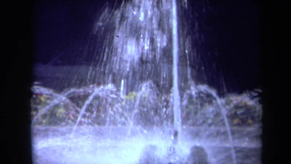 1969 California 8mm frame with multiple fountain sprays arcing outward over a glowing basin.