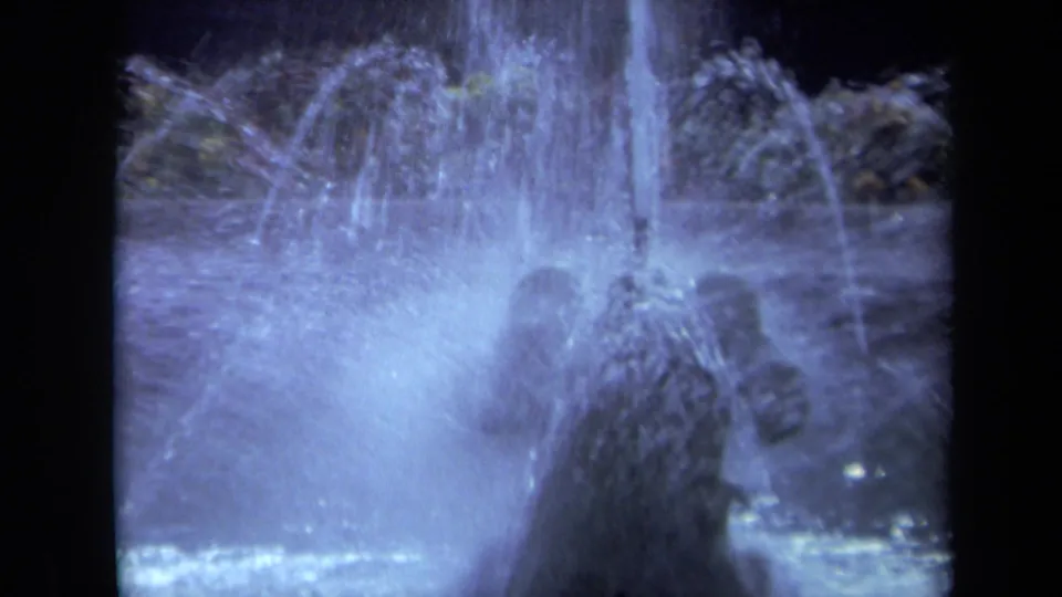 1969 California 8mm frame showing dense fountain spray, mist, and water turbulence in cool night light.