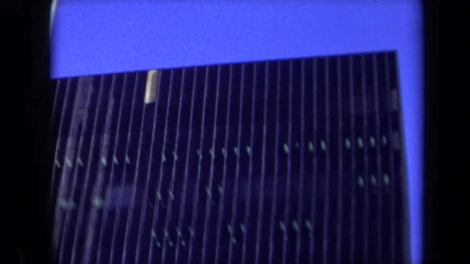 1969 California frame showing the upper portion of a modern high-rise facade, with vertical ribs, dark glass, and blue dusk light.
