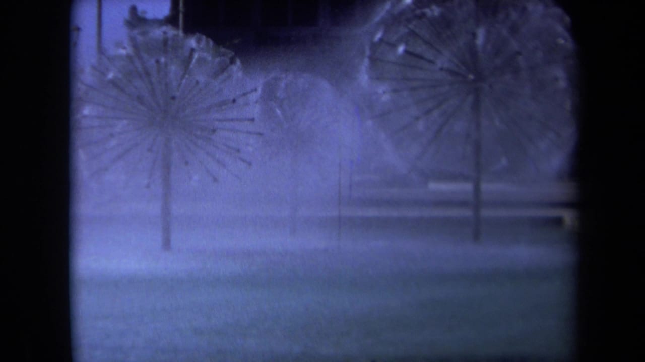 1969 Sacramento 8mm frame showing two starburst fountain sprays through mist with dark architectural edges and blue-purple color shift.