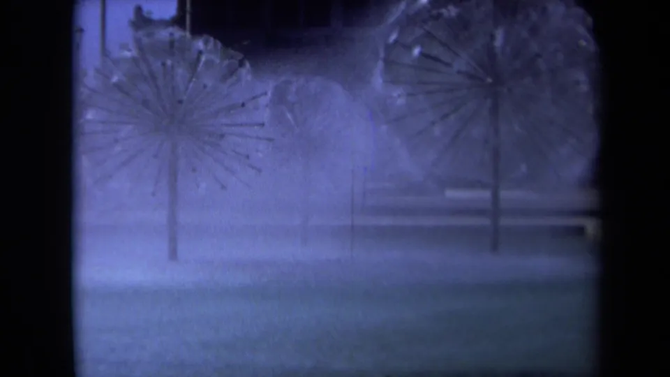 1969 Sacramento 8mm frame showing two starburst fountain sprays through mist with dark architectural edges and blue-purple color shift.
