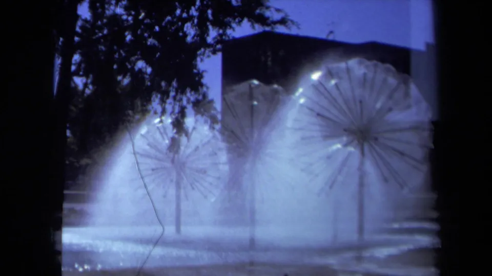 1969 Sacramento night frame with multiple dandelion-shaped sprinklers producing bright water arcs in blue 8mm exposure.