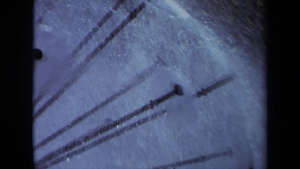 Final 1969 Sacramento 8mm frame showing cropped sprinkler spokes and mist, with soft focus and blue film cast.