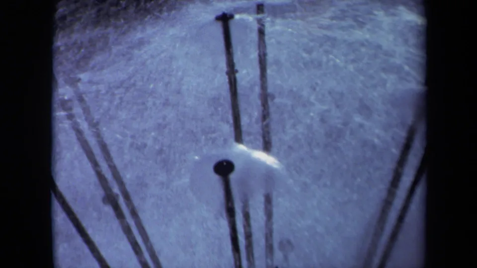1969 Sacramento 8mm frame with a small sprinkler head and black poles radiating through a blue-tinted close-up.
