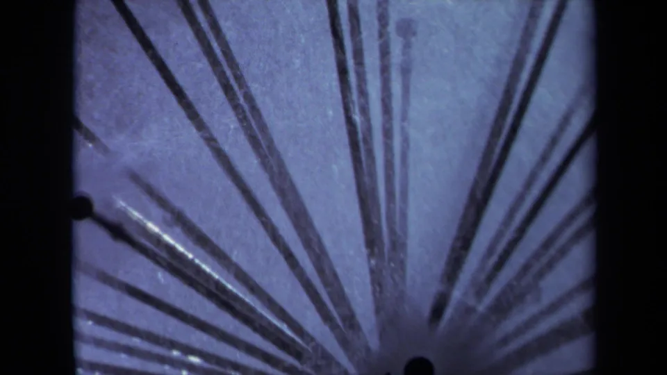 1969 Sacramento 8mm frame showing black sprinkler rods fanning outward with a pale blue textured background and dark film edge.