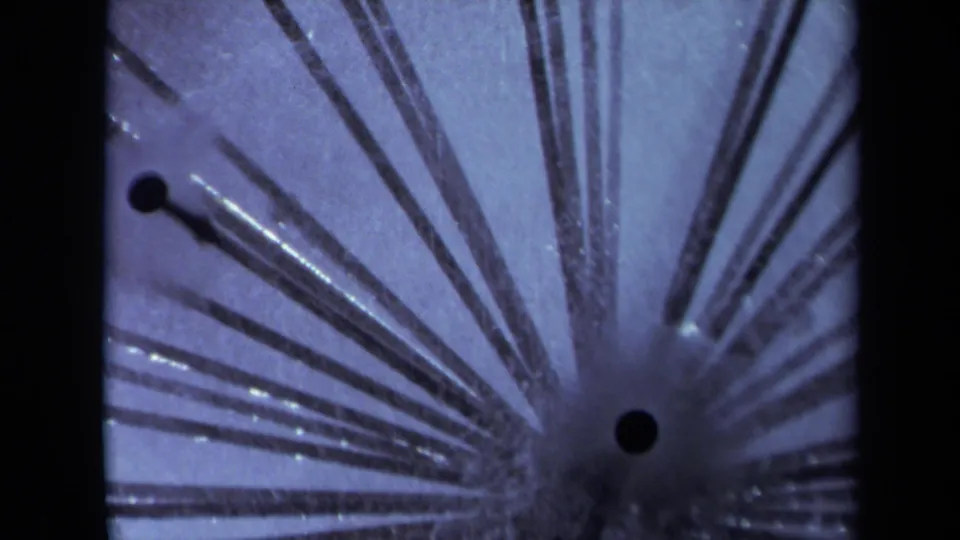 1969 Sacramento 8mm close-up showing radial conductive stems, a dark contact point, and blue-purple scientific demonstration texture.