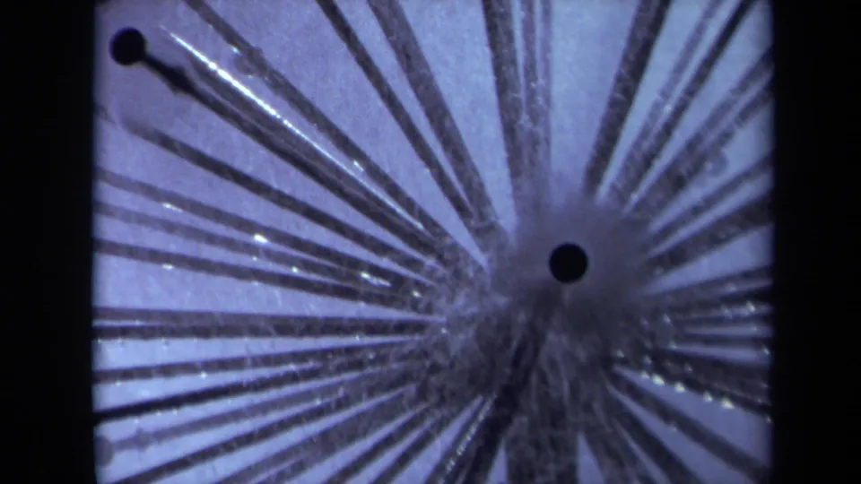 1969 Sacramento 8mm frame with multiple conductive stems radiating across a blue-purple scientific experiment close-up.