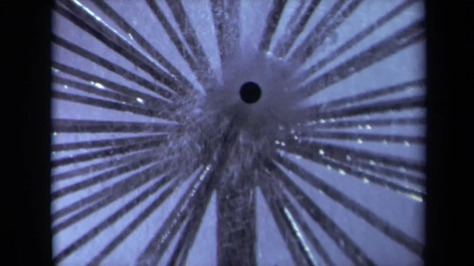 1969 Sacramento 8mm close-up of dense radial stems around a dark contact point, with grain and soft exposure variation.