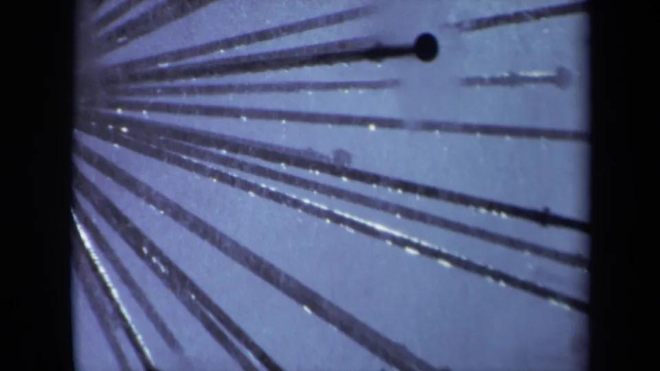 1969 Sacramento 8mm close-up of a metal sprinkler pattern, with dark radial tubes, fine water spray, and blue film tint.