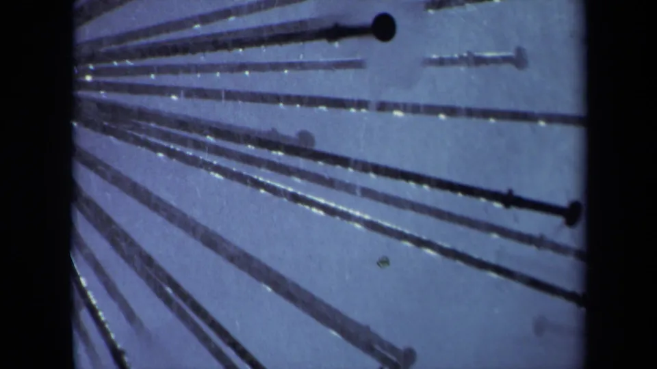 1969 Sacramento 8mm frame showing metal sprinkler tubes, dark end caps, and small water droplets against a blue-toned background.