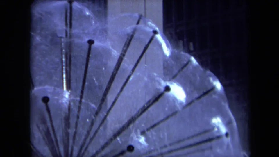1969 Sacramento 8mm frame with the sprinkler globe shifted right, showing rods, dark nozzles, and fine spray.
