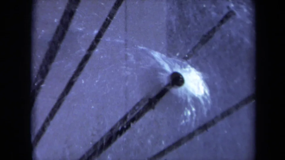 Final 1969 Sacramento 8mm frame focusing on a dark sprinkler nozzle, radiating rods, and mist over the translucent globe.