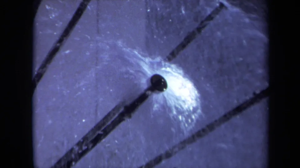 1969 Sacramento 8mm frame showing a sprinkler nozzle and bright water spray against a cool-toned pale background.