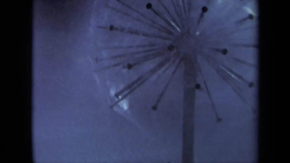 1969 Sacramento 8mm frame showing the sprinkler from a wider angle, with radiating arms or spray paths softened by motion.