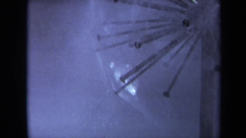 1969 Sacramento 8mm frame showing a wet reflective surface with radial metal rods, nail-like heads, grain, and black frame borders.