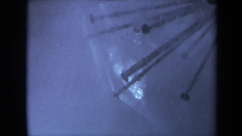 1969 Sacramento 8mm frame with a wet surface, umbrella-like radial metal detail, blue cast, speckling, and soft focus.