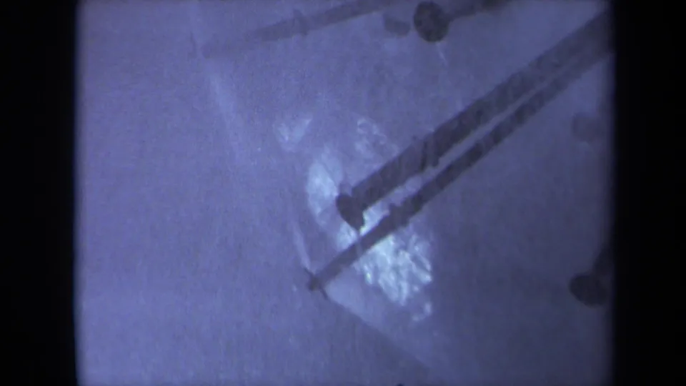 1969 Sacramento 8mm frame of diagonal metal strips and droplets on a wet reflective surface, with blue tint and right-side frame border.