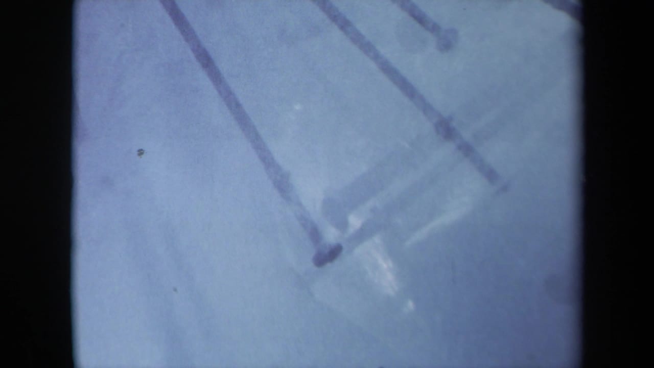 1969 Sacramento 8mm frame showing a soft close-up of nail heads and shafts crossing a pale blue surface.