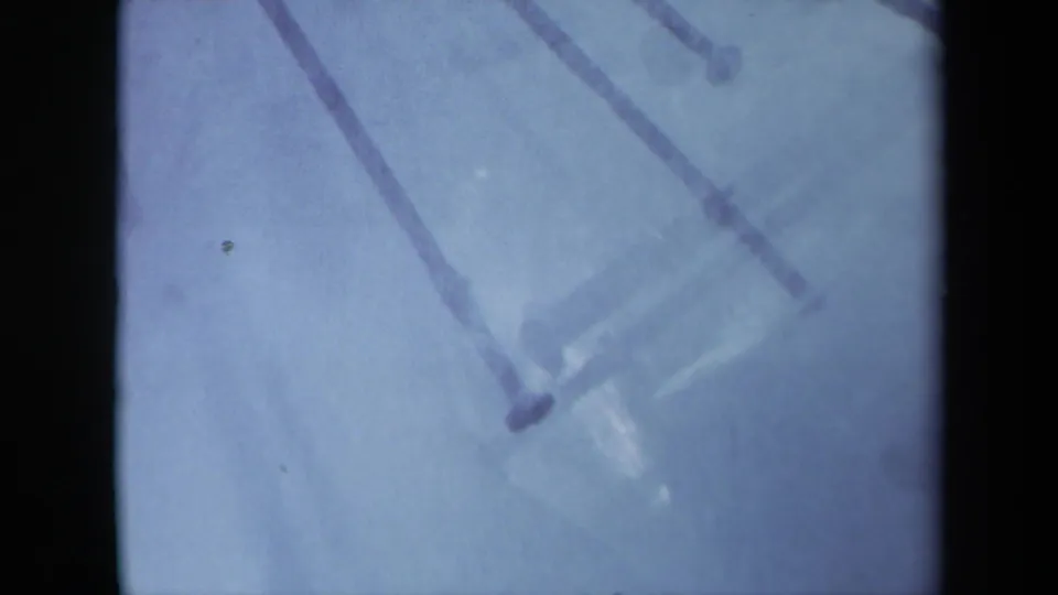 1969 Sacramento 8mm frame showing a soft close-up of nail heads and shafts crossing a pale blue surface.