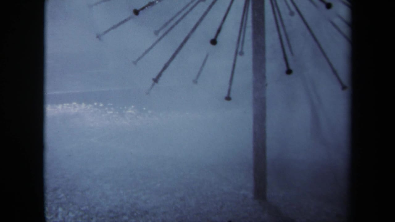 1969 Sacramento 8mm frame showing a radiating metal structure above rain-dark pavement and a muted gray sky.