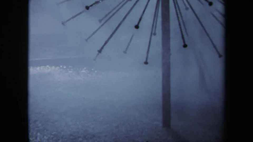 1969 Sacramento 8mm frame showing a radiating metal structure above rain-dark pavement and a muted gray sky.