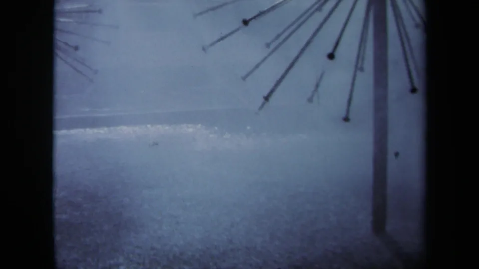 1969 Sacramento frame with a spiked metal form and vertical pole against damp pavement and a blue-gray sky.