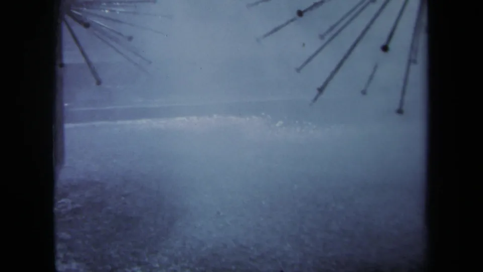 1969 Sacramento 8mm view of slick pavement, a partial radiating metal structure, and overcast sky.