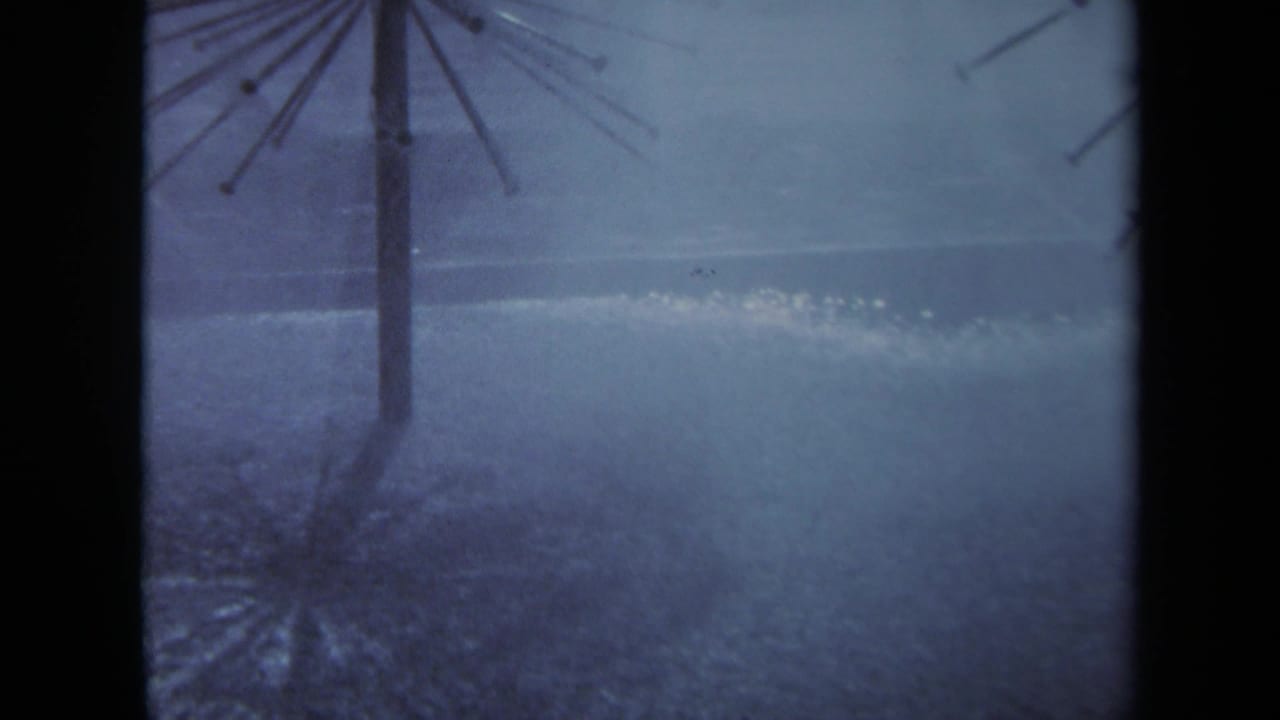 Spoked umbrella stand in heavy rain with pooled water and blue-gray storm light.