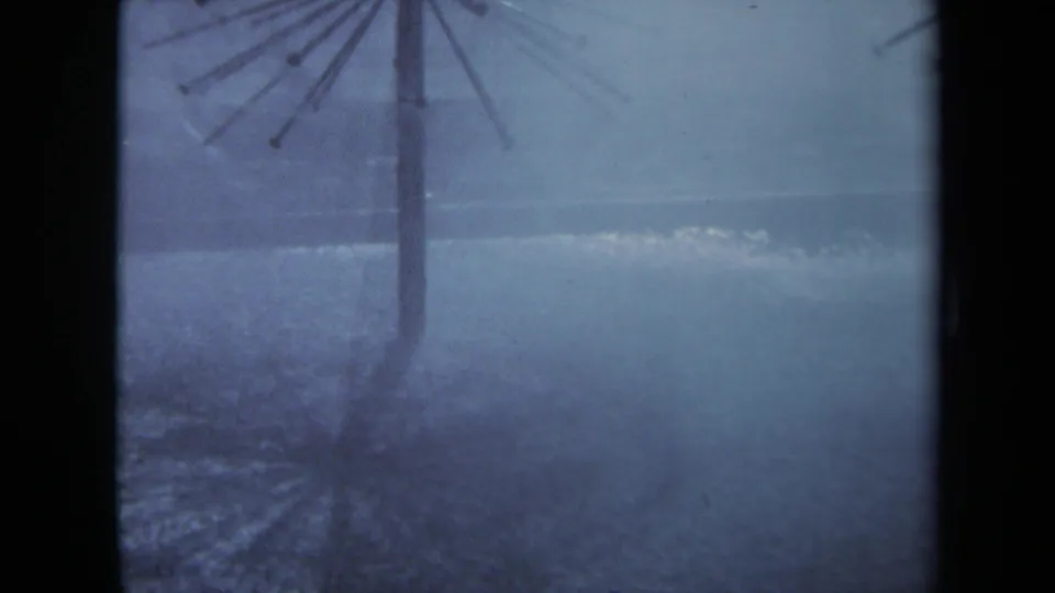 1969 Sacramento storm frame with a vertical umbrella support and spoked top silhouetted against rain and pooled water.