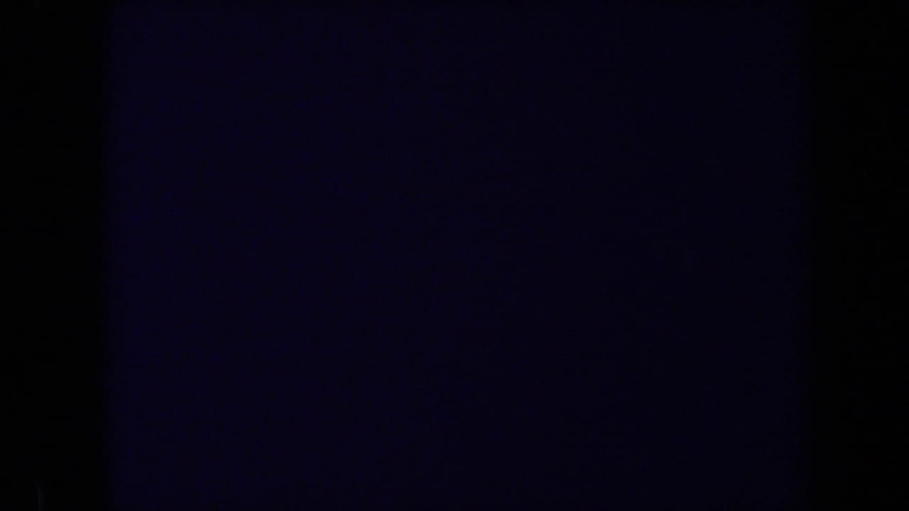 Very dark frame with only faint blue-purple exposure and film edge shadows visible.