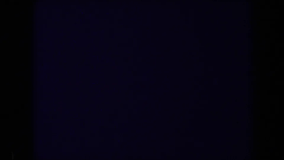 Mostly underexposed 8mm frame from the Sacramento clip, with a faint blue-purple field and heavy dark borders.