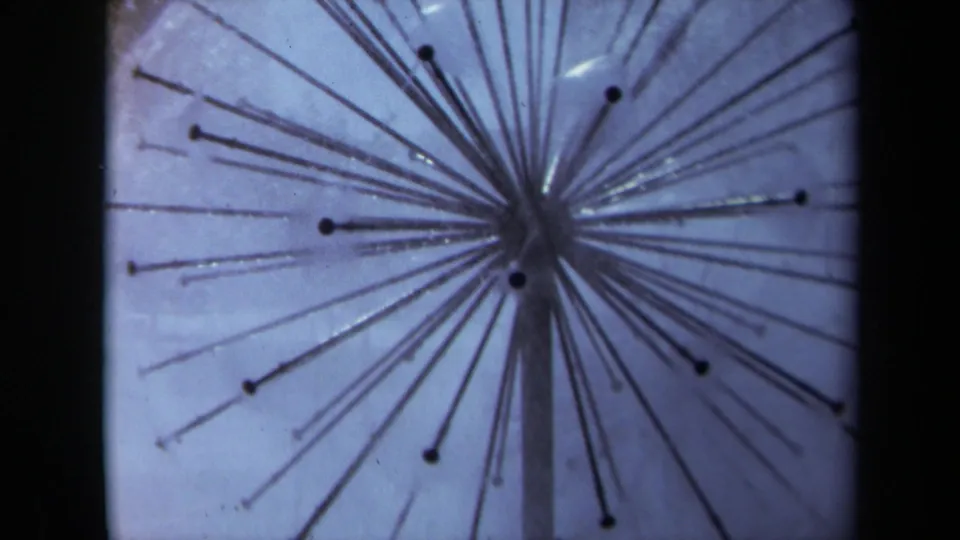 1969 Sacramento 8mm frame with a closer blue-toned view of rods radiating from a central hub on a vertical support.