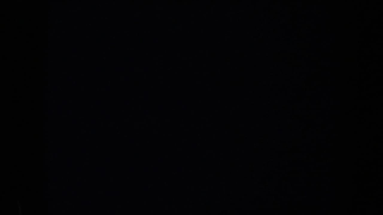 Mostly dark frame with faint film texture and no clear subject.