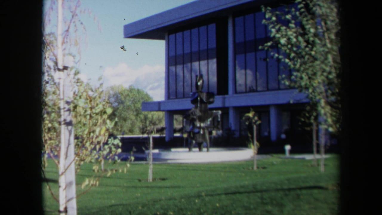 Modern office building with abstract fountain sculpture on a lawn.
