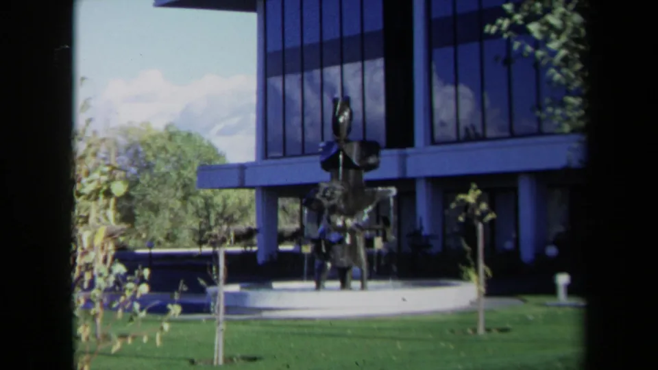 Sacramento 1969 frame with the camera closer to the abstract fountain sculpture and the blue-and-white modern office facade.