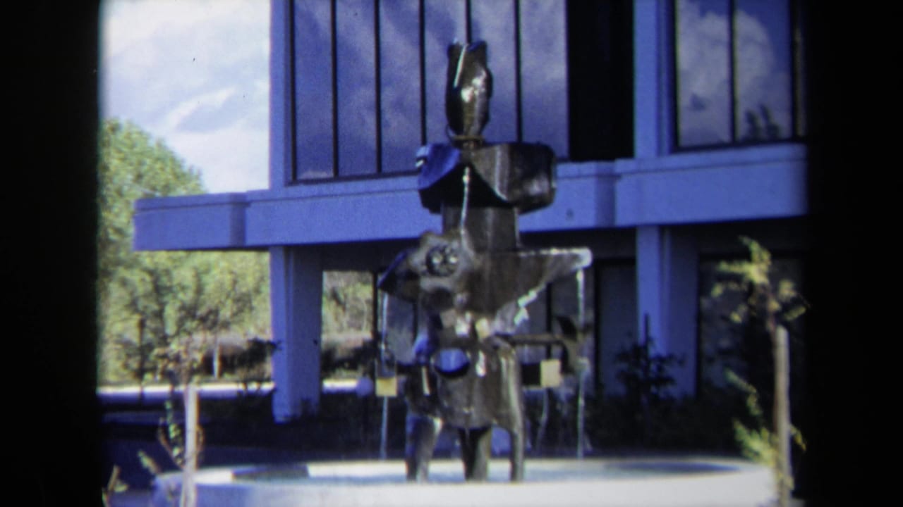 Abstract metal fountain sculpture in front of a modern building.