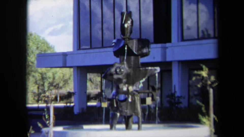 1969 Sacramento 8mm frame showing an abstract metal fountain sculpture near a modern windowed building and landscaped grounds.