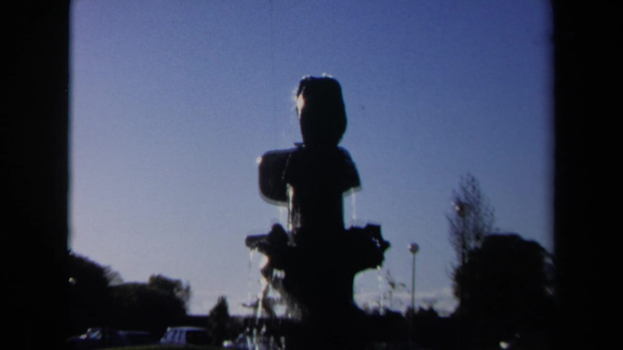 Silhouetted fountain centered against blue sky with water visible at the base.