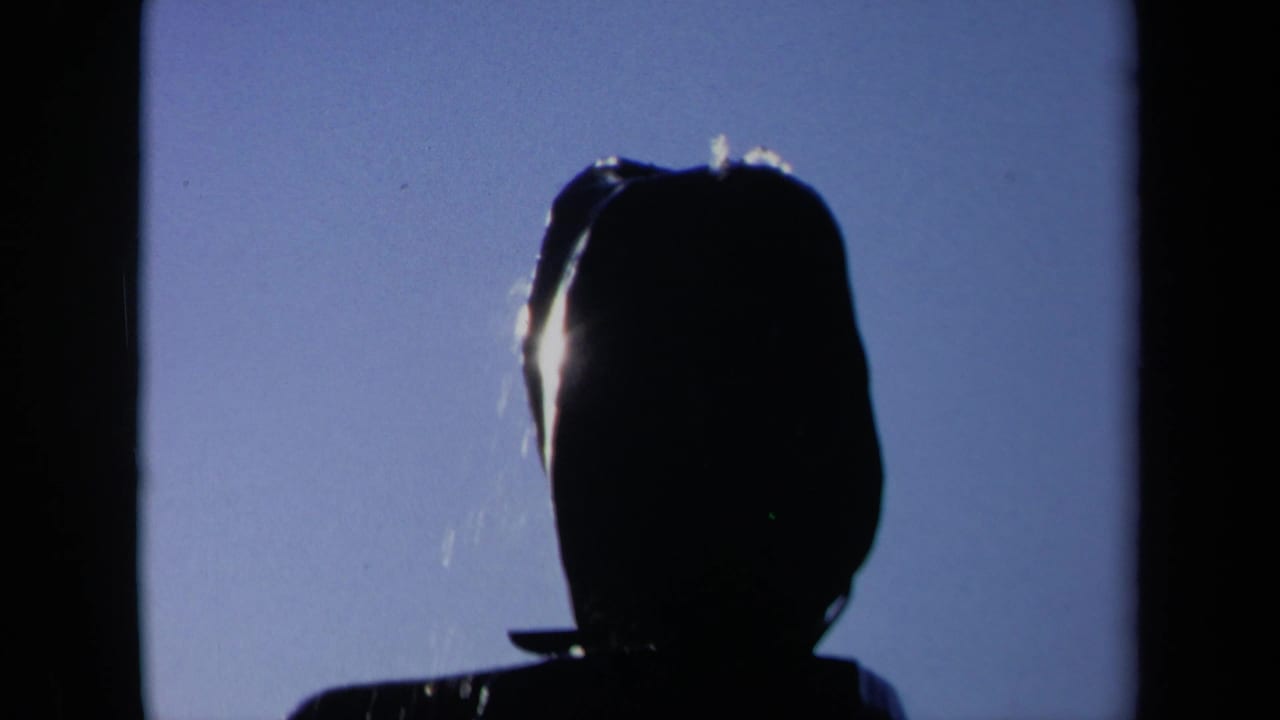 1969 Sacramento 8mm frame showing a dark head-and-shoulders silhouette against blue sky as water begins to fall across the figure.