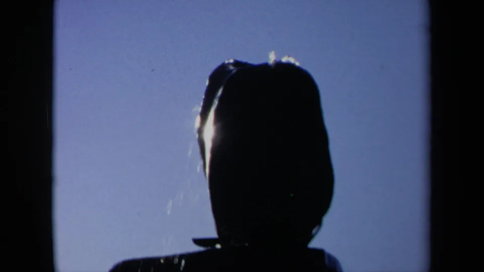 1969 Sacramento 8mm frame showing a dark head-and-shoulders silhouette against blue sky as water begins to fall across the figure.