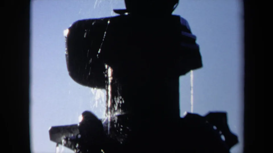 1969 Sacramento 8mm frame showing a tightly framed dark silhouette as water pours down across the head, shoulder, and upper body area.