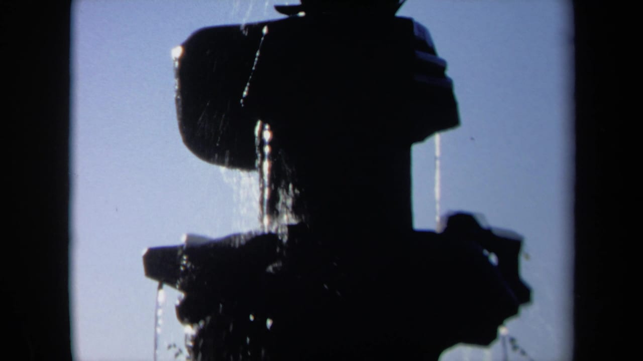A 1969 Sacramento 8mm frame shows a dark sculptural fountain silhouette with streams of water falling in bright daylight.