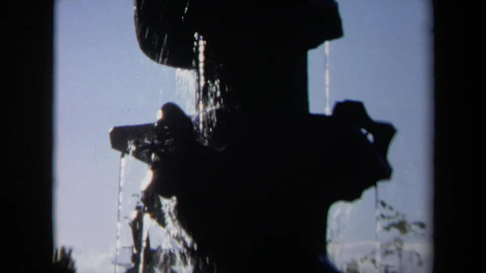A backlit 1969 Sacramento fountain appears as a dark geometric silhouette, with water spilling downward across the frame.