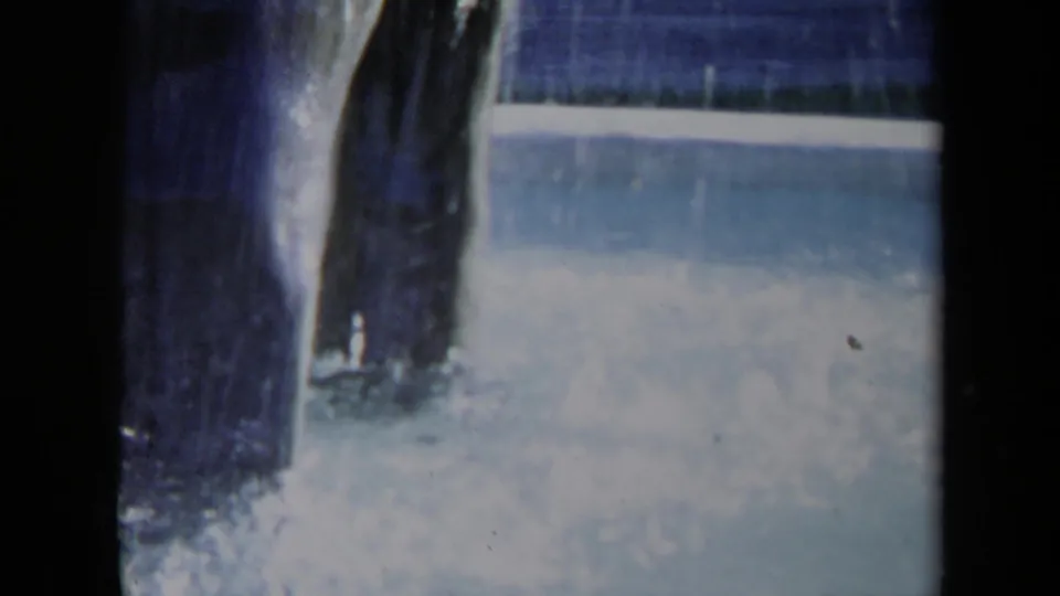Close 8mm view of the Sacramento fountain, with water sheeting down a dark sculptural surface into the blue-white basin below.