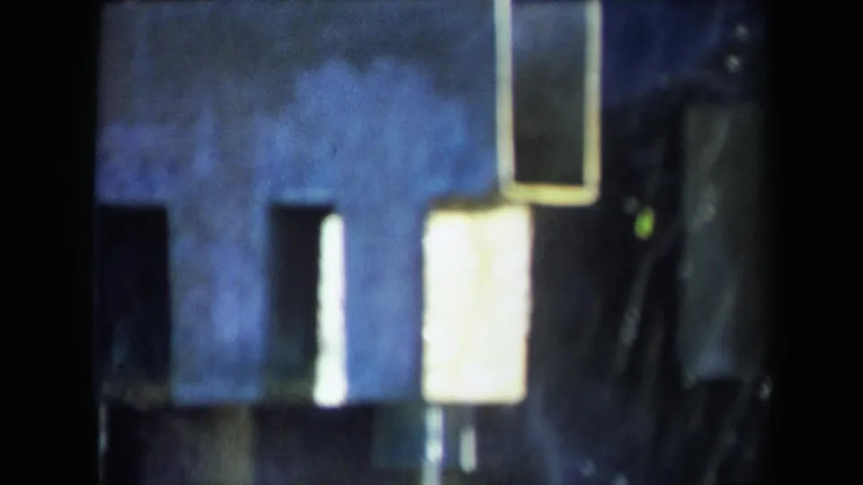 1969 Sacramento 8mm frame with blue-toned machinery, bright reflections, and heavy grain.